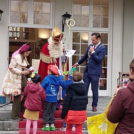 Sint, burgemeester en kinderburgemeester in actie met kinderen.