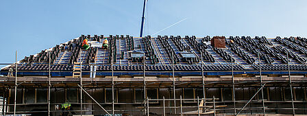 Dak van woningen in aanbouw, mannen op dak aan het werk.