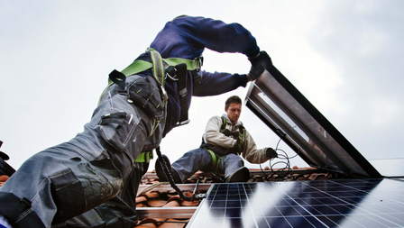 Twee mannen op het dak leggen zonnepanelen aan